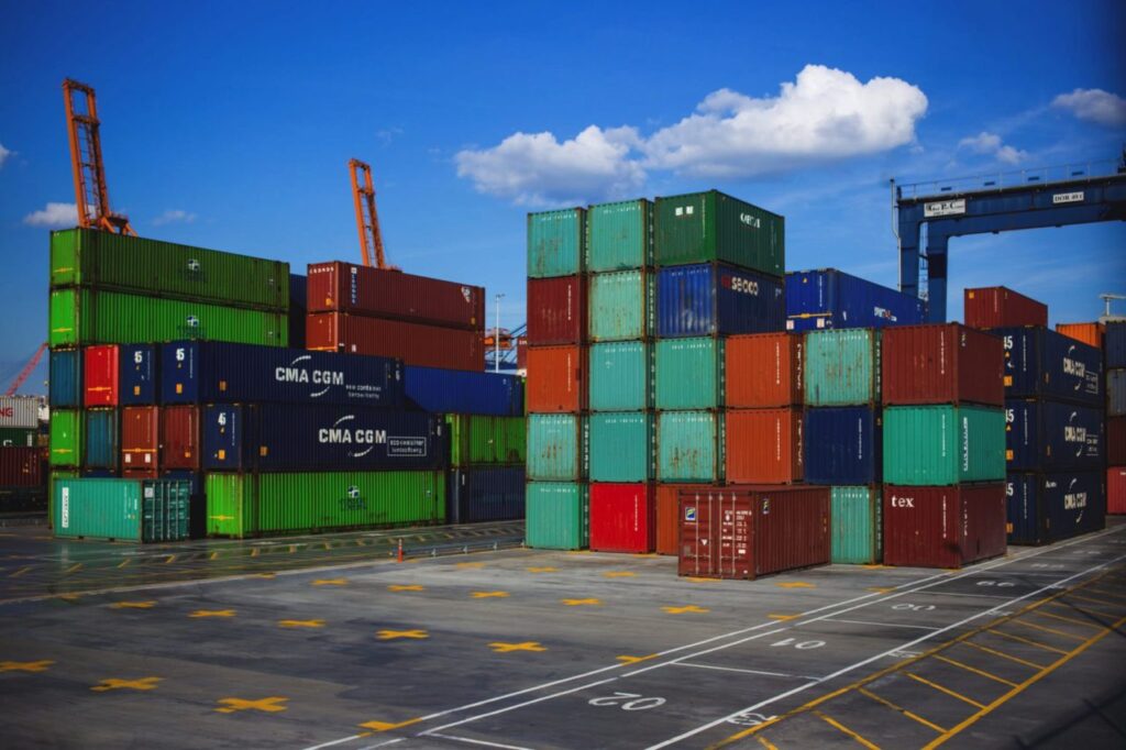 "Stacked colorful shipping containers at a port terminal, symbolizing global trade and logistics."