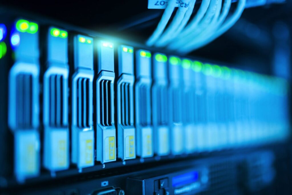 Close-up of illuminated server rack with multiple network cables and active status lights in a data center environment.