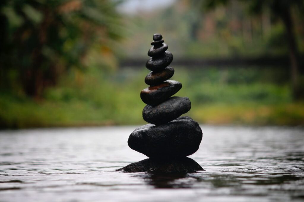 "Stacked stones balanced in a river, representing tranquility and mindfulness in nature."