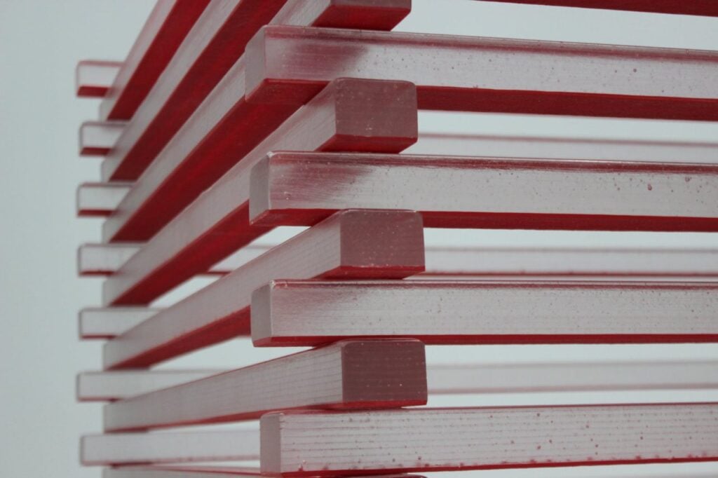 "Stacked red acrylic panels creating an abstract geometric pattern, showcasing modern art and design."