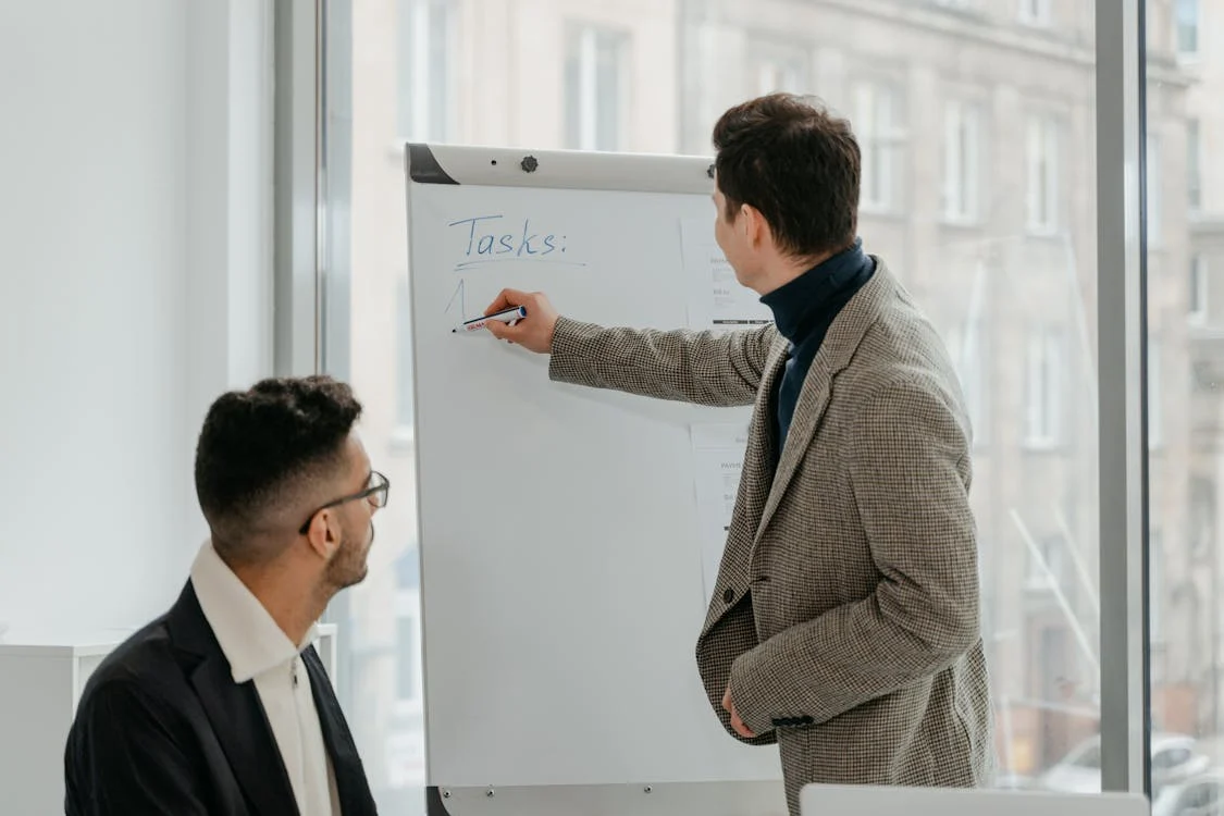 "Business meeting with professionals discussing tasks on a flip chart in a modern office setting"