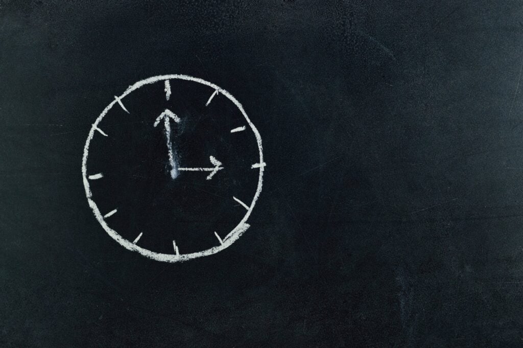 "Chalk-drawn clock on blackboard symbolizing starting point for learning Python basics."